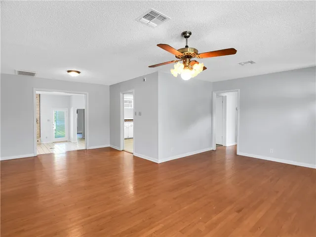 a view of an empty room with window and a chandelier fan