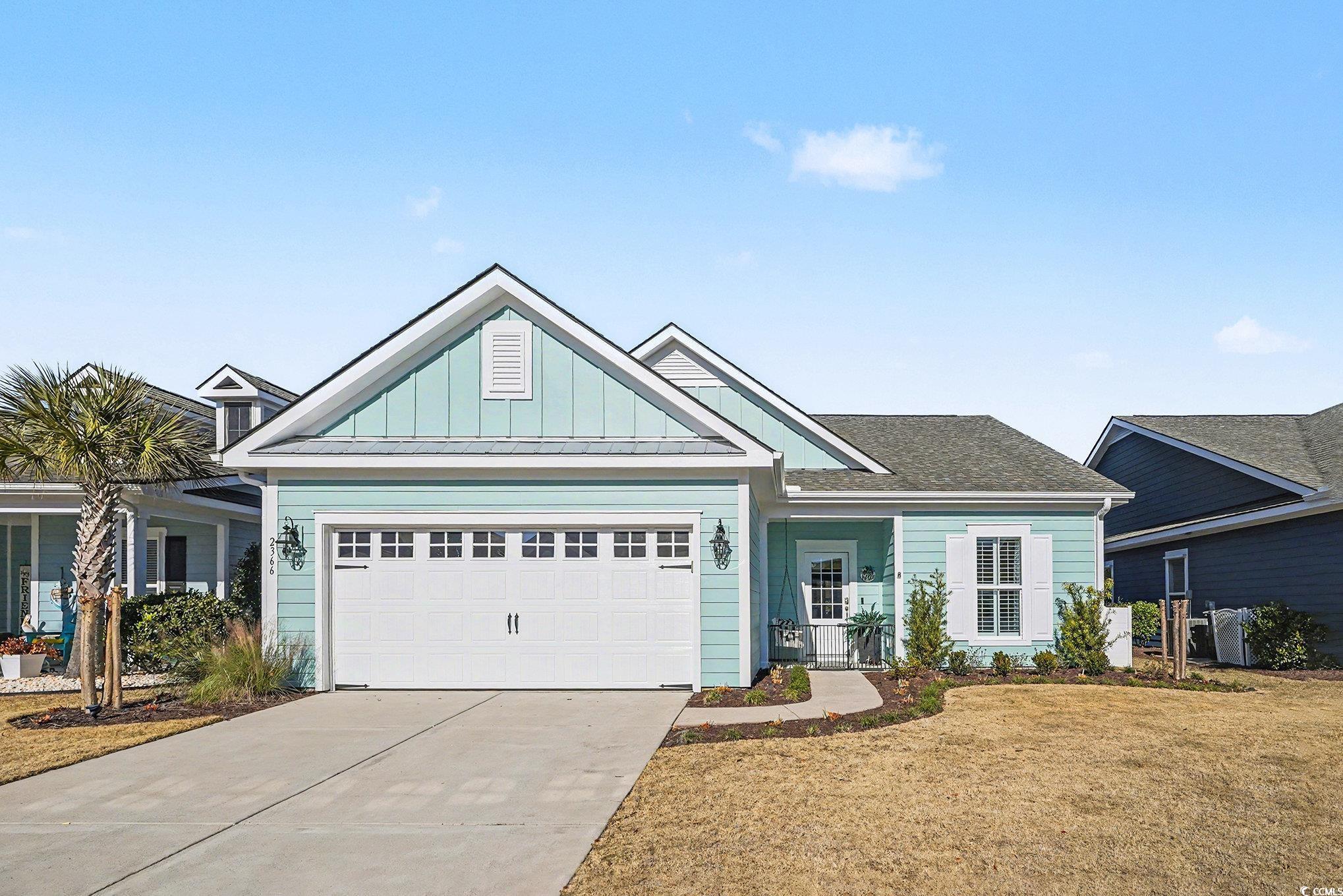 View of front of home with board and batten siding, concrete driveway, a garage, a front lawn, and a shingled roof