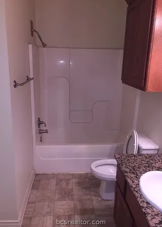 a bathroom with a granite countertop toilet a sink and bathtub