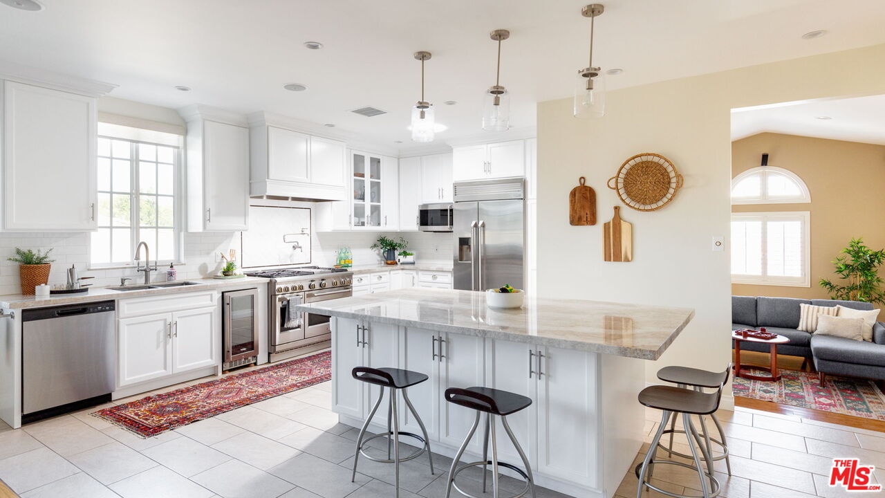 3810 Hauser Boulevard Los Angeles, CA 90008 - Photo 8 of 32 a kitchen with stainless steel appliances kitchen island granite countertop a stove a sink a dining table and chairs with wooden floor