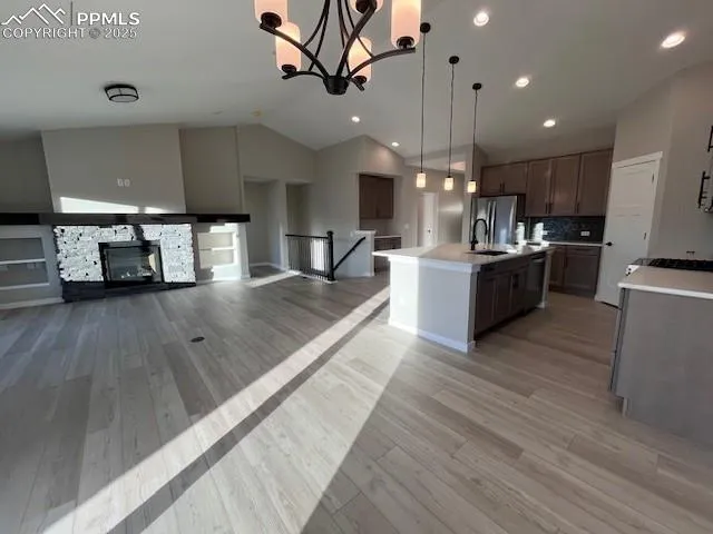 a large kitchen with kitchen island a stove a sink dishwasher and a dining table with wooden floor