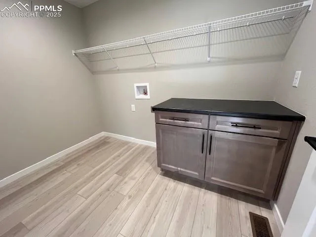 a view of a kitchen with wooden floor and white cabinets