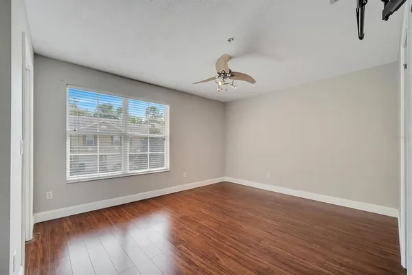 a view of an empty room with wooden floor and a window