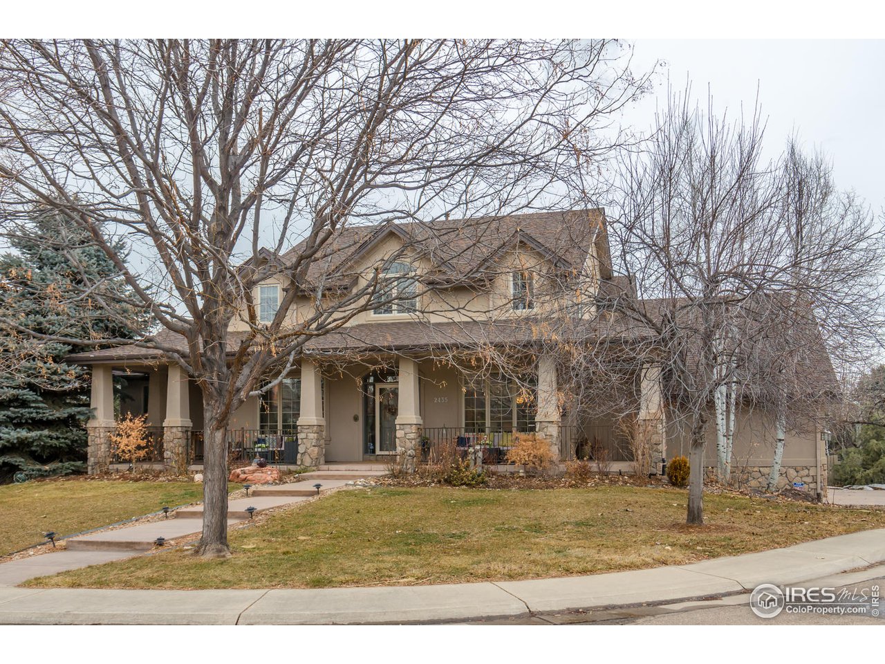 a view of a white house with a large tree and wooden fence
