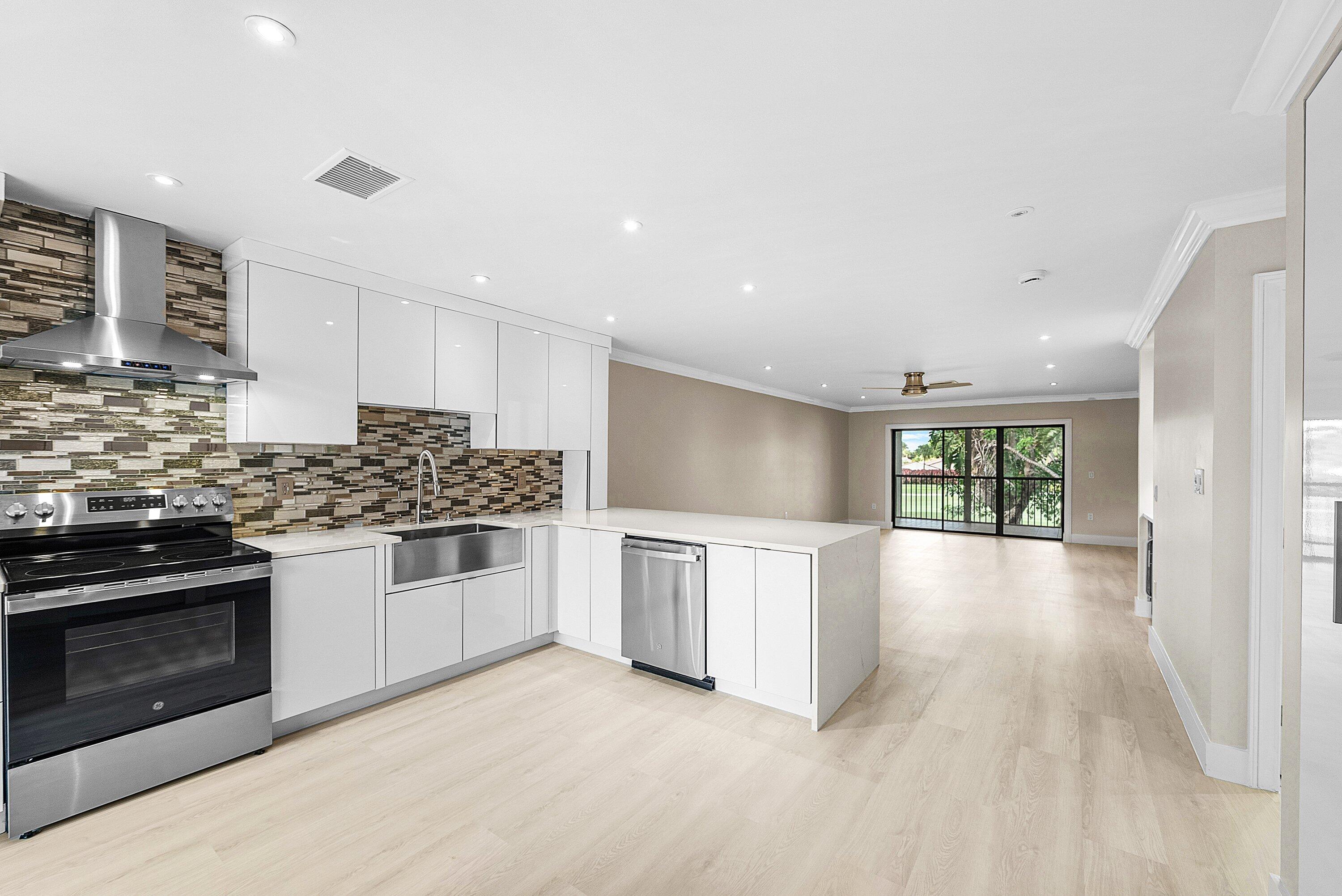 18 Stratford Drive East, Unit F Boynton Beach, FL 33436 - Photo 11 of 54 a kitchen with stainless steel appliances kitchen island granite countertop a stove and a sink
