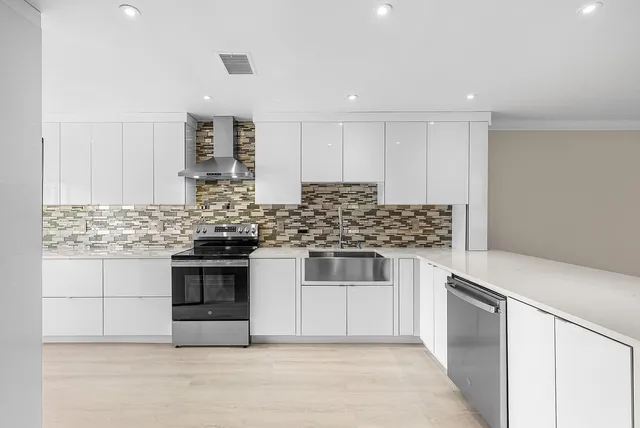 a kitchen with stainless steel appliances granite countertop a stove and white cabinets