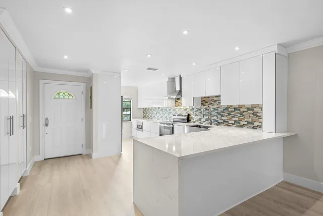 a large white kitchen with a sink and refrigerator