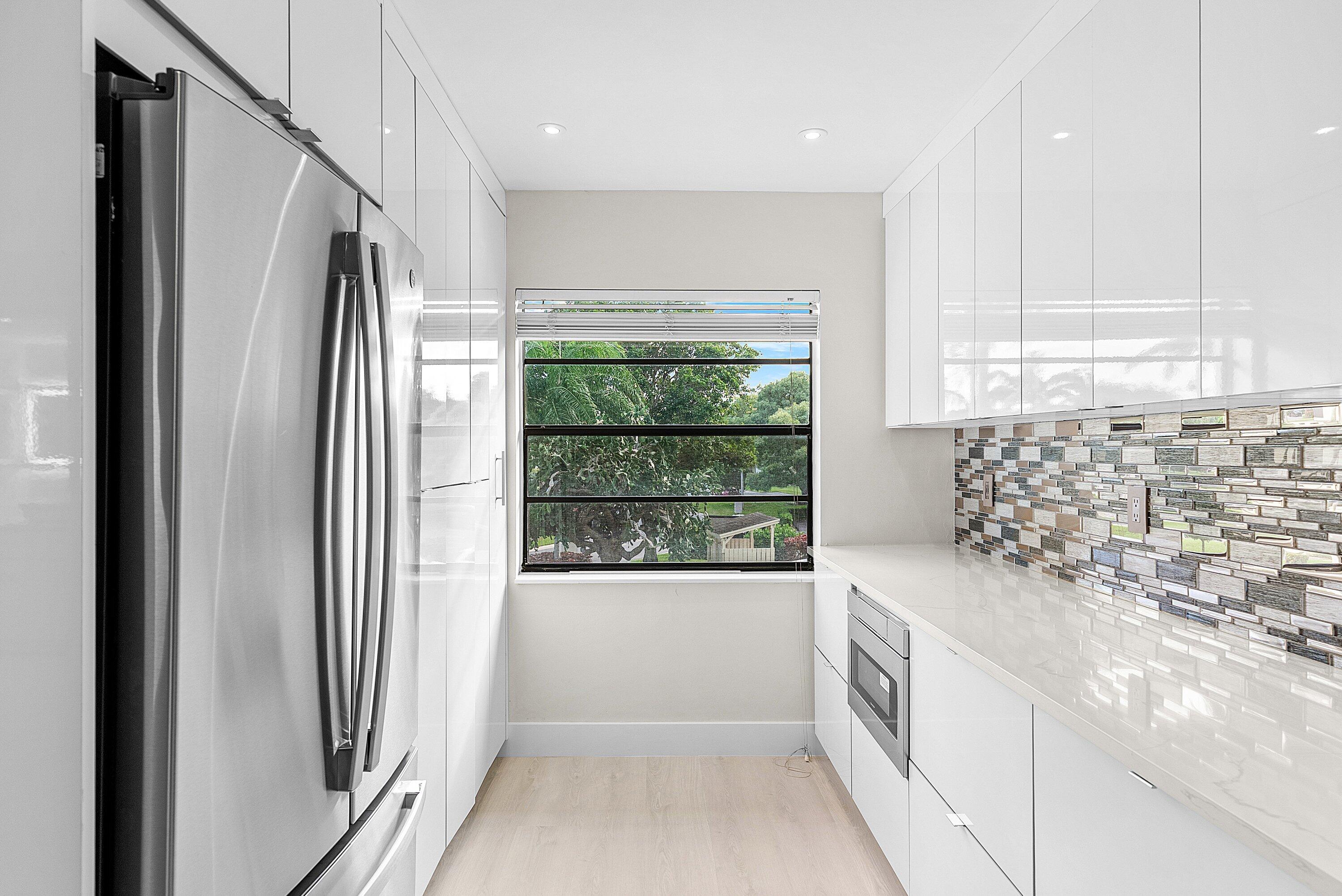 18 Stratford Drive East, Unit F Boynton Beach, FL 33436 - Photo 15 of 54 a kitchen with stainless steel appliances granite countertop a refrigerator and a sink