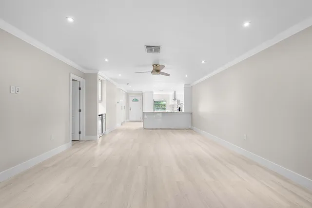an empty room with wooden floor fan and windows