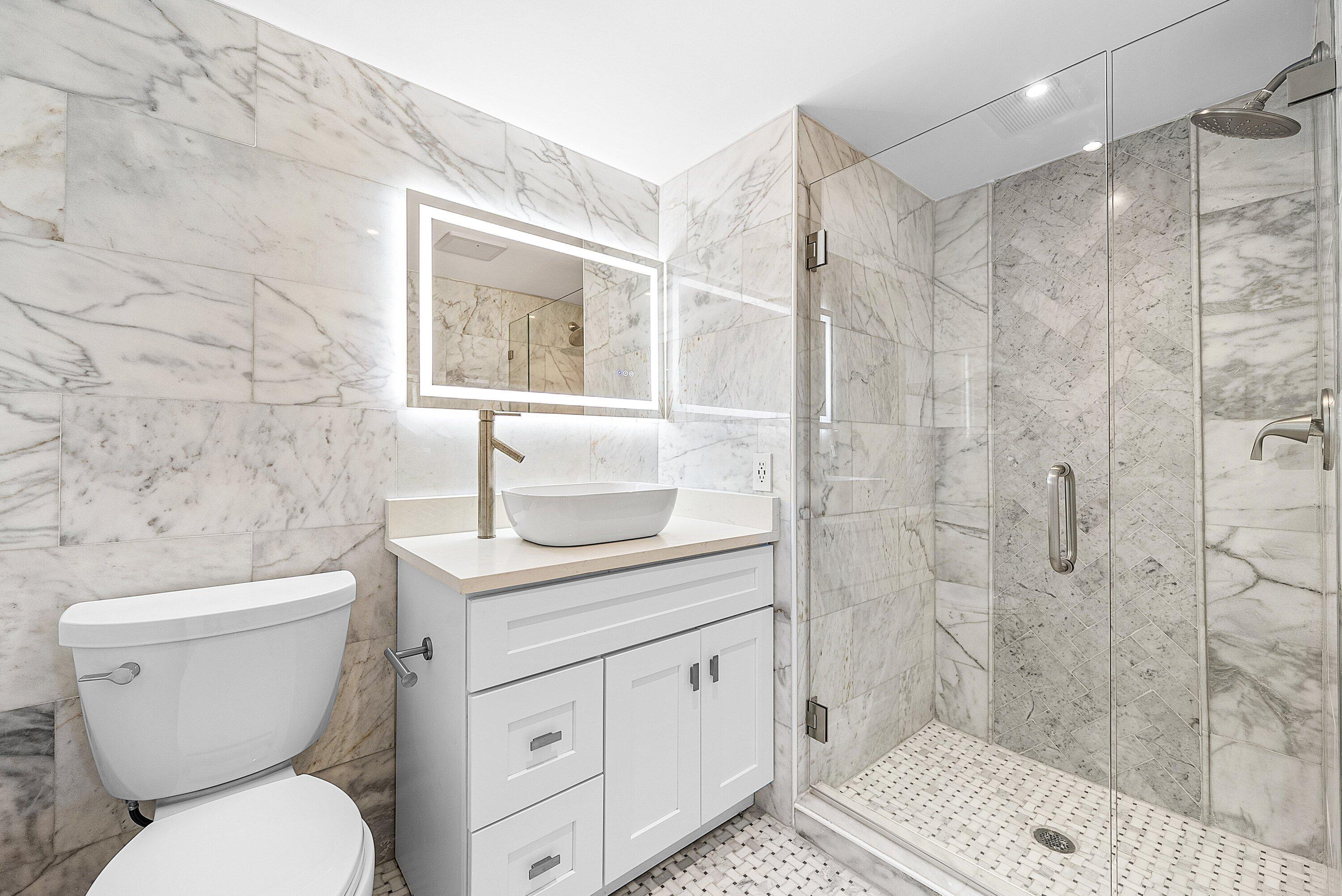 18 Stratford Drive East, Unit F Boynton Beach, FL 33436 - Photo 5 of 54 a bathroom with a granite countertop toilet a sink and a shower