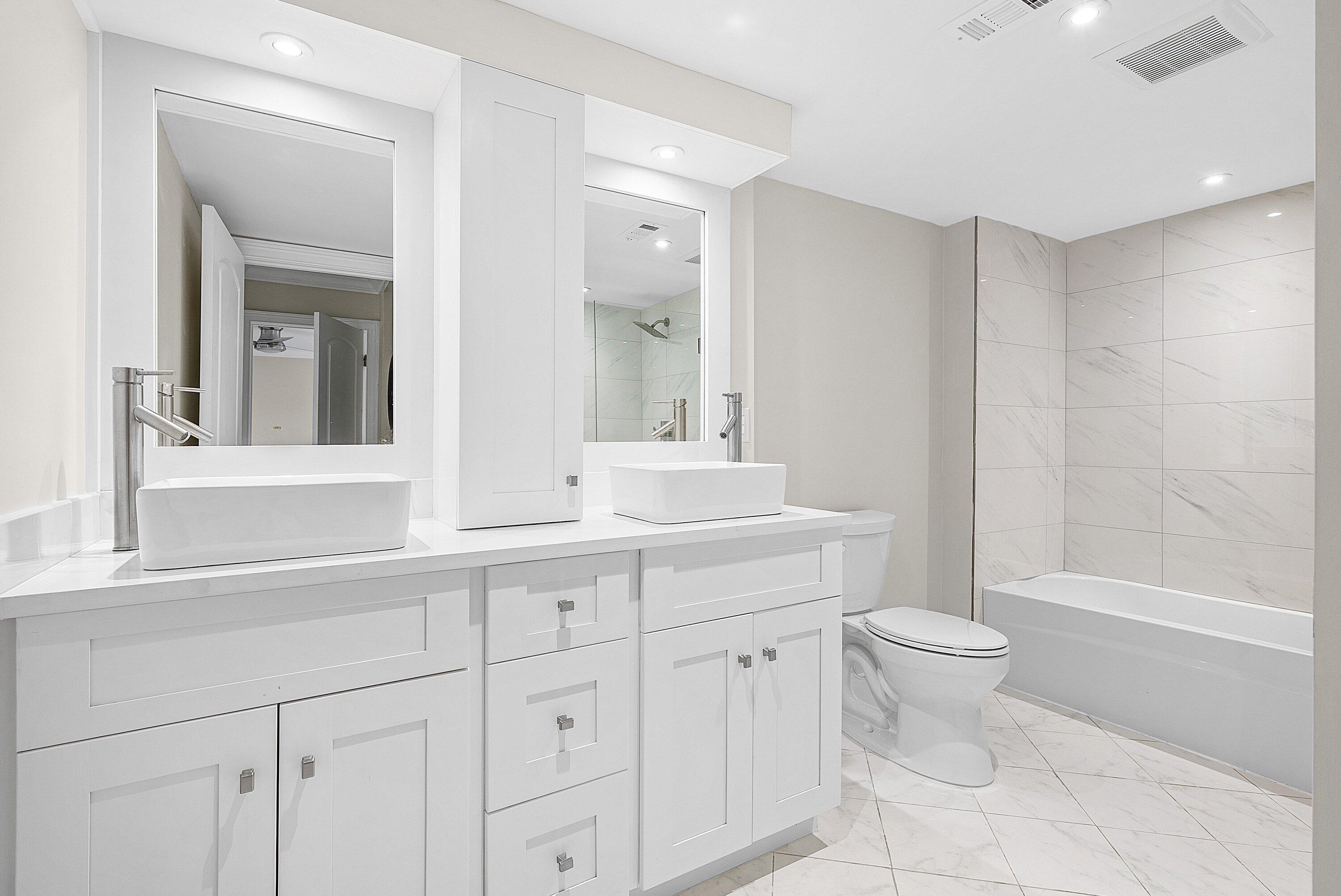 18 Stratford Drive East, Unit F Boynton Beach, FL 33436 - Photo 8 of 54 a bathroom with a toilet a sink a mirror a bathtub and vanity