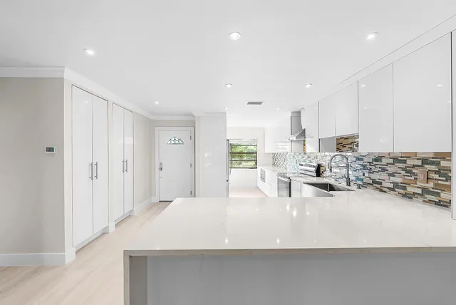 a large white kitchen with kitchen island a sink stainless steel appliances and cabinets