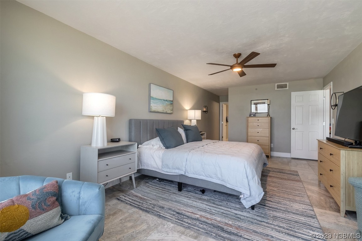 4545 South Atlantic Avenue, Unit 3204 Ponce Inlet, FL 32127 - Photo 29 of 58 a bedroom with a bed a chandelier and a couch