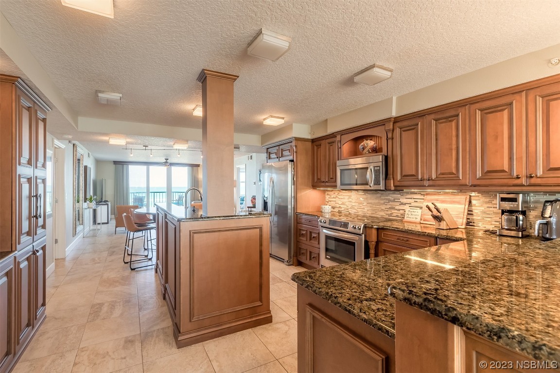 4545 South Atlantic Avenue, Unit 3204 Ponce Inlet, FL 32127 - Photo 39 of 58 a kitchen with stainless steel appliances granite countertop a stove top oven a sink a dining table and chairs with wooden floor