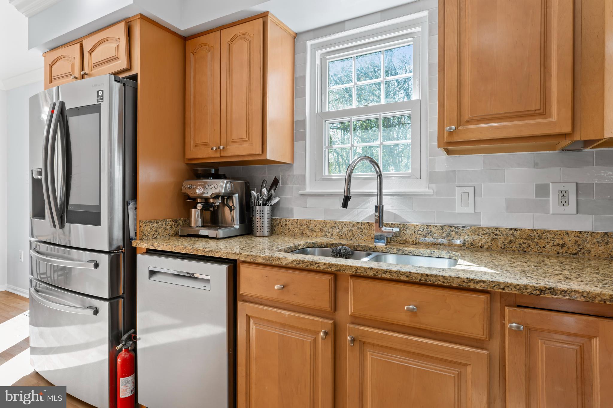 10267 Green Holly Terrace Silver Spring, MD 20902 - Photo 15 of 52 a kitchen with granite countertop stainless steel appliances a sink window and cabinets