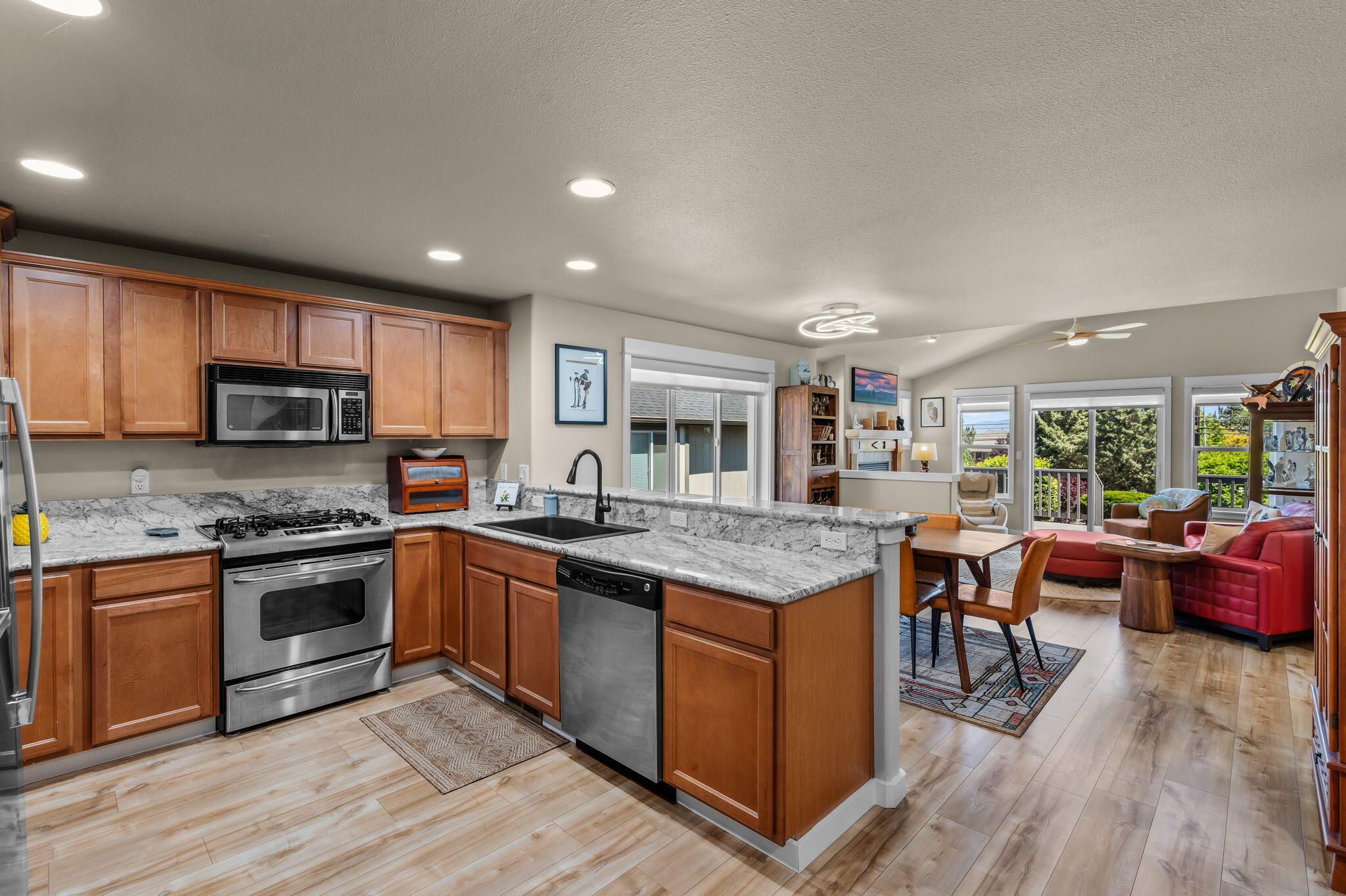 3714 Southwest 29th Street Redmond, OR 97756 - Photo 4 of 21 a kitchen with stainless steel appliances granite countertop a stove top oven a sink dishwasher a dining table and chairs with wooden floor