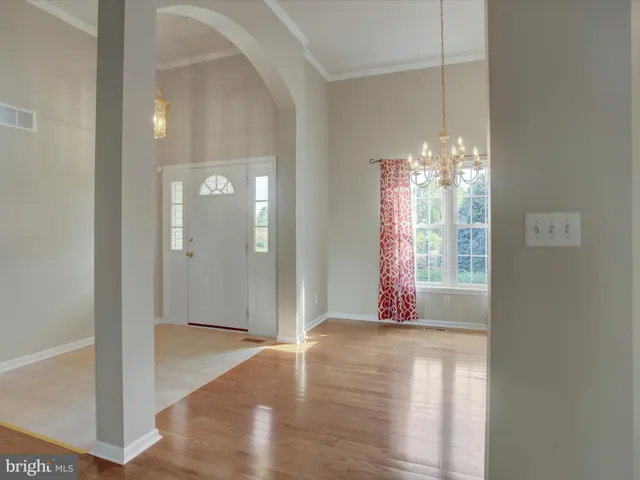 a view of an empty room with wooden floor and a bathroom
