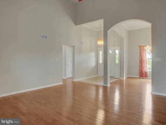 a view of an empty room with chandelier fan