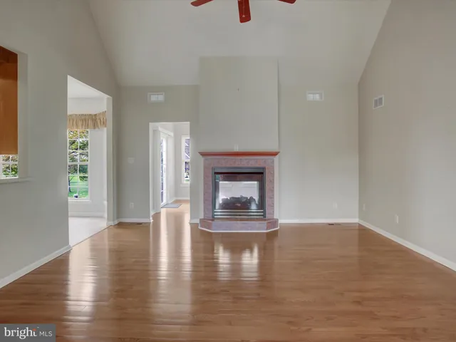 an empty room with wooden floor fireplace and windows