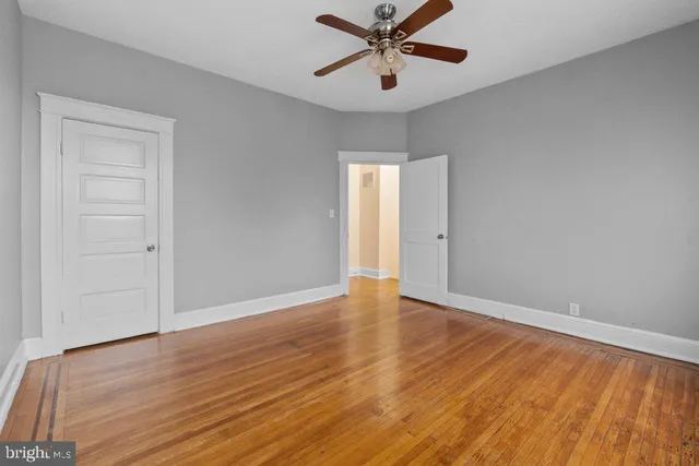 an empty room with wooden floor closet and windows