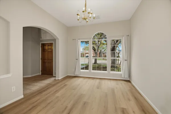 a view of an empty room with window and wooden floor