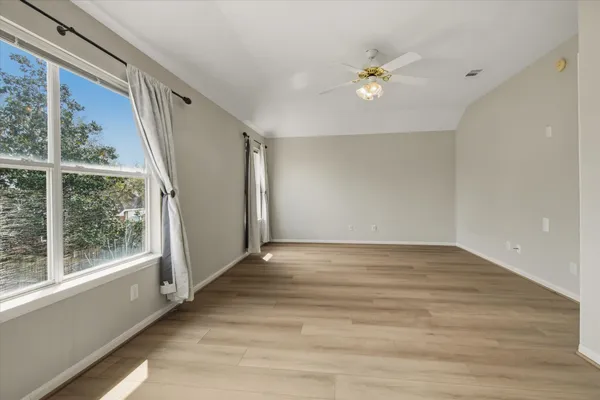 a view of an empty room with wooden floor and a window