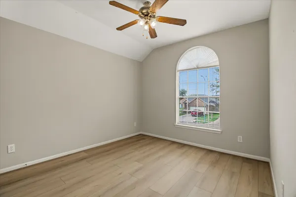 an empty room with a window and a ceiling fan