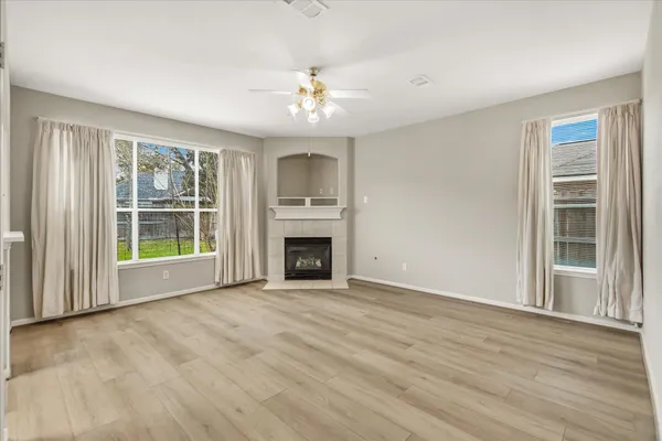 a view of an empty room with a window and wooden floor