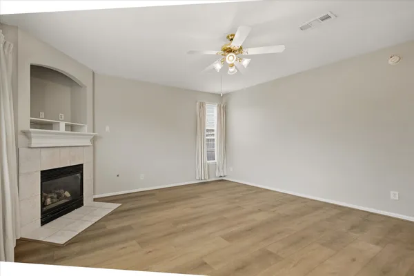 a view of an empty room with chandelier fan and fire place