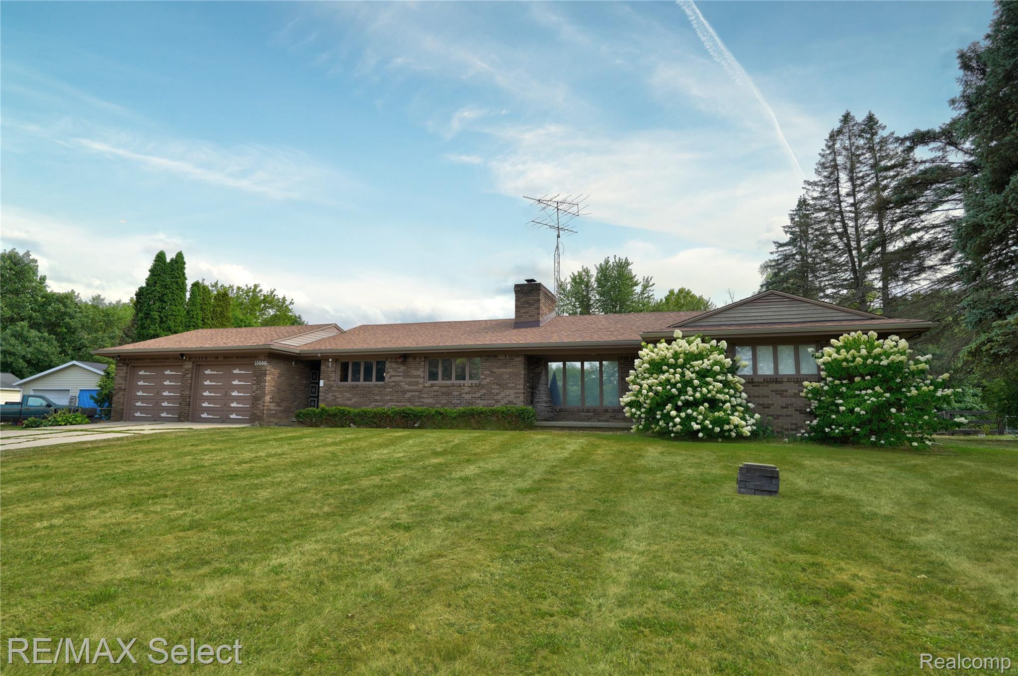 11080 Lapeer Road Davison, MI 48423 - Photo 17 of 64 Brick exterior with a three-car garage, mature landscaping, and a broad front lawn