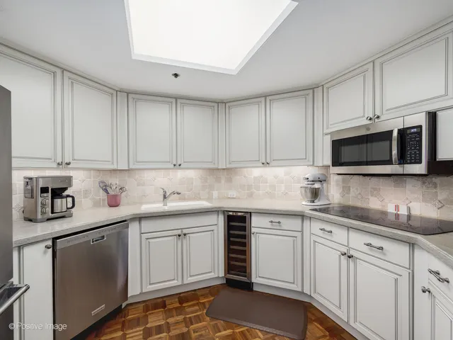 a kitchen with stainless steel appliances granite countertop a refrigerator a sink a stove and white cabinets