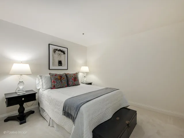 a bedroom with a bed and a lamp on dresser