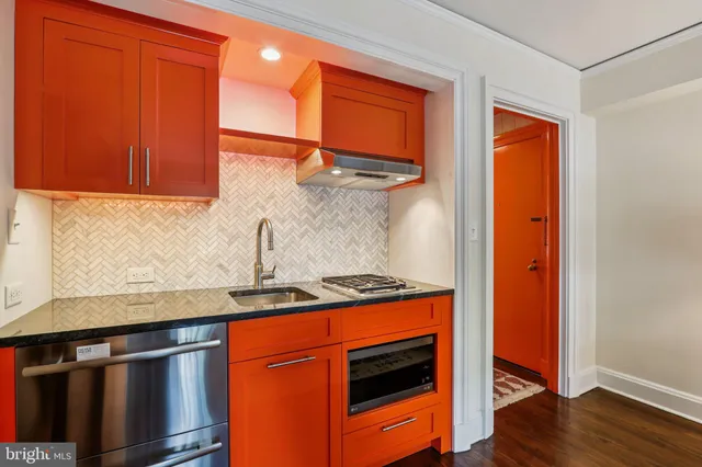 a kitchen with stainless steel appliances granite countertop wooden cabinets and a wooden floor