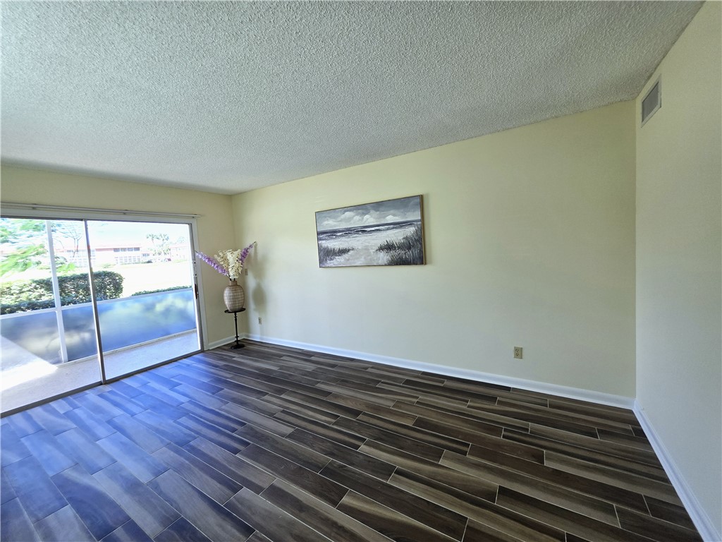88 Crooked Tree Lane, Unit 107 Vero Beach, FL 32962 - Photo 14 of 33 a view of an empty room with wooden floor and a window