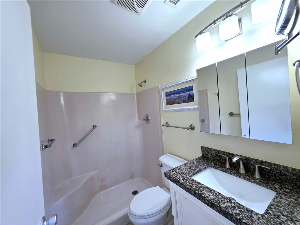 88 Crooked Tree Lane, Unit 107 Vero Beach, FL 32962 - Photo 22 of 33 a bathroom with a granite countertop sink a mirror a toilet and shower