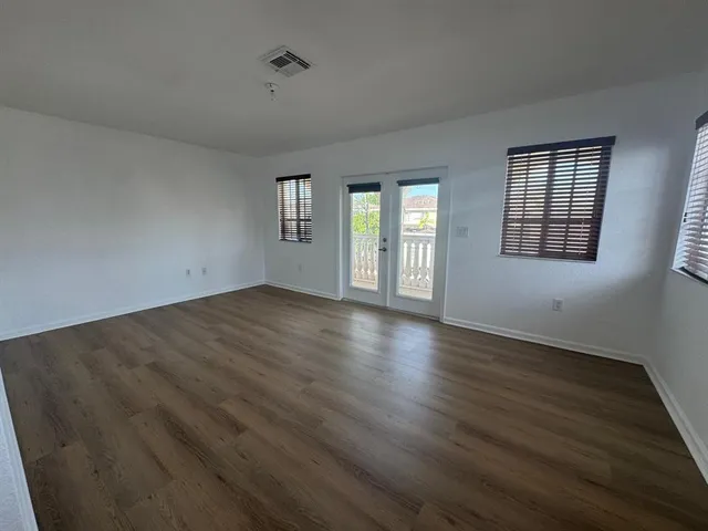 an empty room with wooden floor and windows