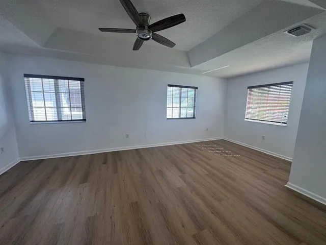 a view of empty room with wooden floor and fan