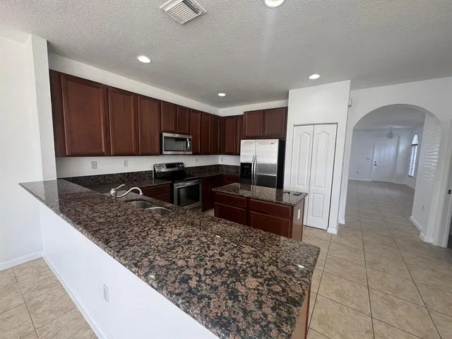 a kitchen with stainless steel appliances granite countertop a stove refrigerator sink and cabinets