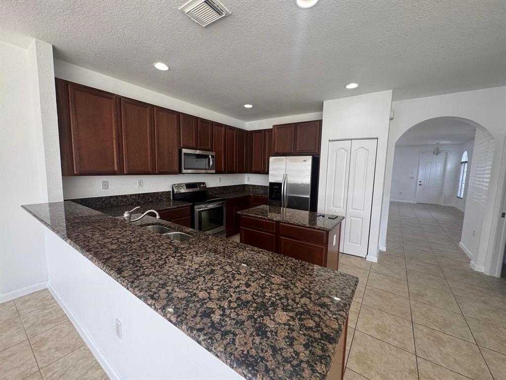 14044 Southwest 276th Way Homestead, FL 33032 - Photo 7 of 26 a kitchen with stainless steel appliances granite countertop a stove refrigerator sink and cabinets