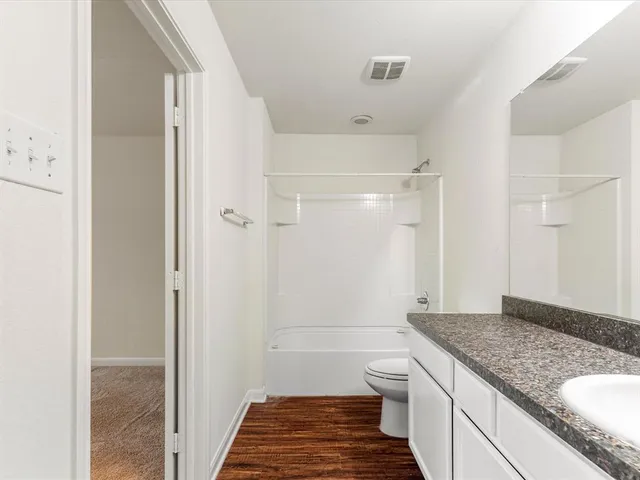 a bathroom with a granite countertop toilet sink and mirror