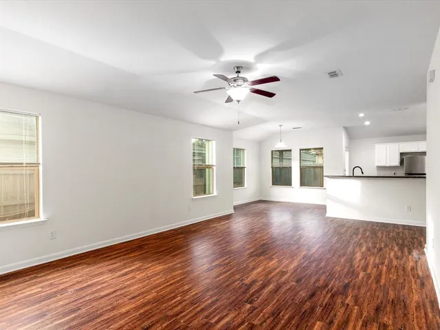 a view of an empty room with window and wooden floor