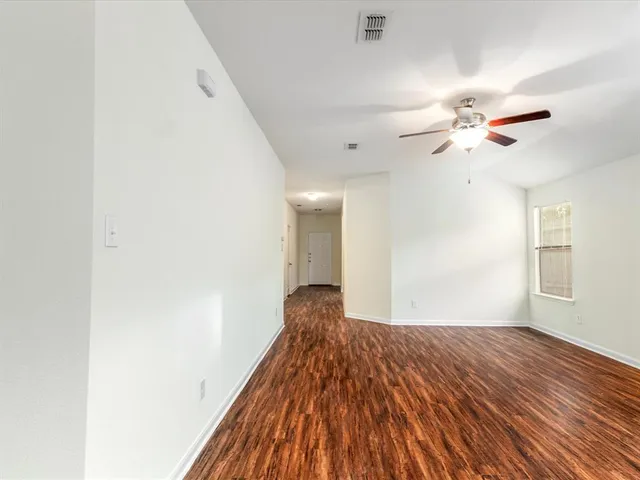 a view of a big room with wooden floor and a chandelier fan