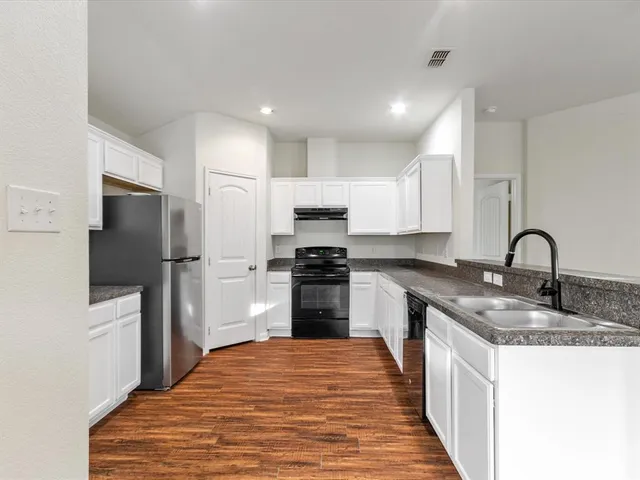 a kitchen with granite countertop a stove and a wooden floors