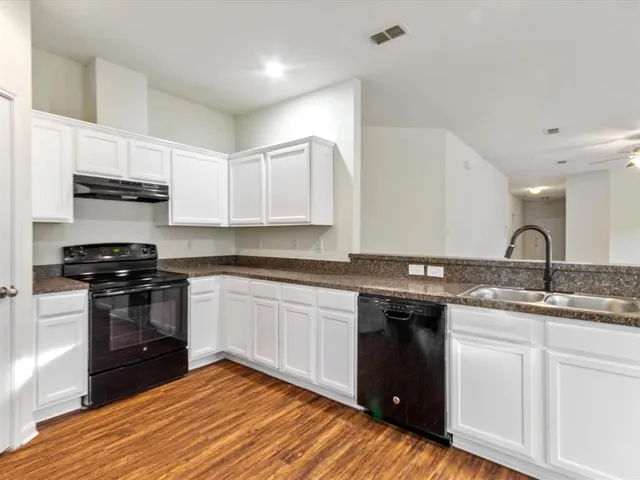 a kitchen with granite countertop a refrigerator stove and sink