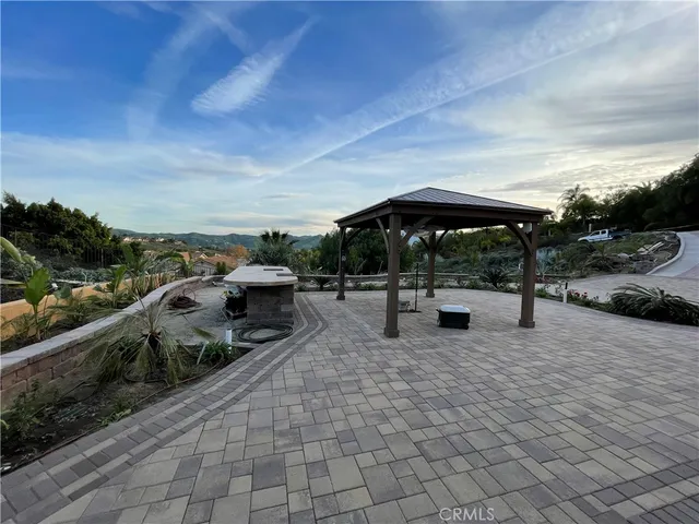 a view of a patio with table and chairs under an umbrella with large trees