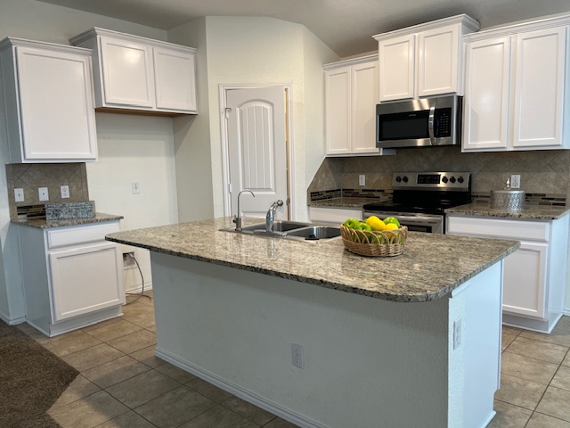 505 Ibis Falls Loop Jarrell, TX 76537 - Photo 2 of 29 a kitchen with granite countertop a sink a stove top oven a counter space and cabinets
