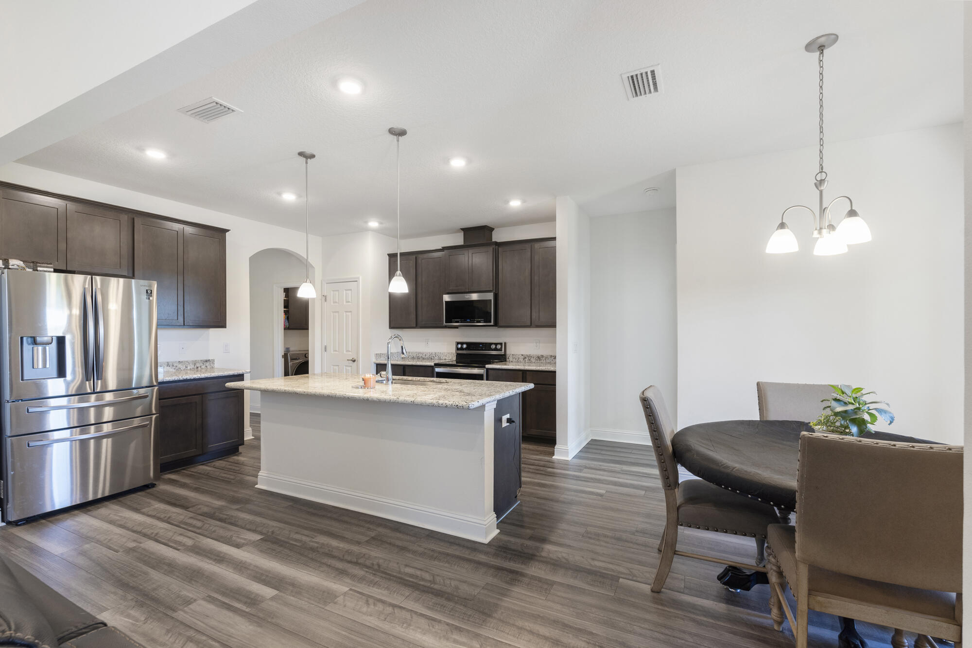 170 Double Eagle Court Freeport, FL 32439 - Photo 13 of 46 a kitchen with stainless steel appliances kitchen island granite countertop a table chairs stove and microwave