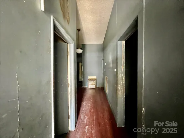 a view of a hallway with wooden floor and a bathroom