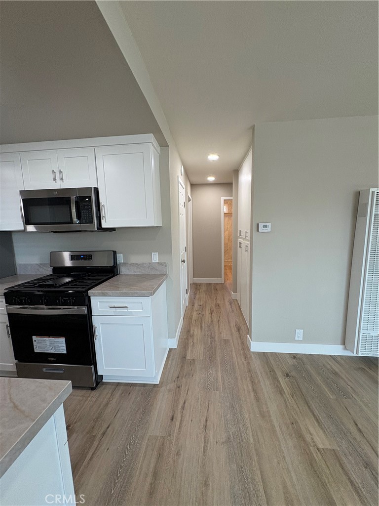 33972 El Encanto Avenue, Unit D Dana Point, CA 92629 - Photo 19 of 46 a kitchen with wooden floors and black appliances