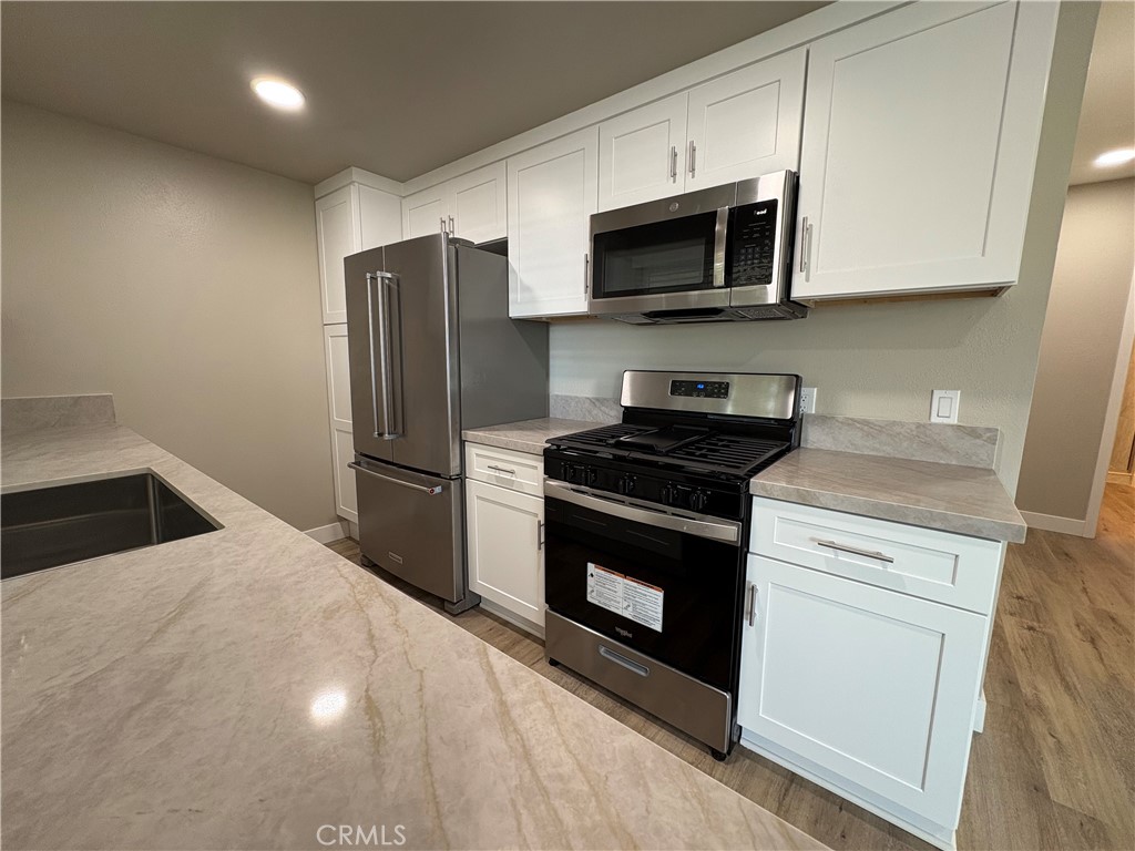 33972 El Encanto Avenue, Unit D Dana Point, CA 92629 - Photo 4 of 46 a kitchen with stainless steel appliances white cabinets and a stove top oven